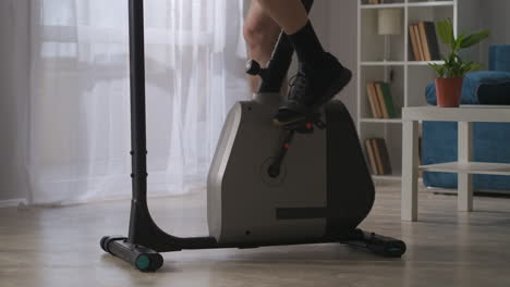 fitness-in-home-man-is-spinning-pedals-of-exercise-bicycle-in-room-closeup-view-of-legs-healthy-lifestyle-and-keeping-fit